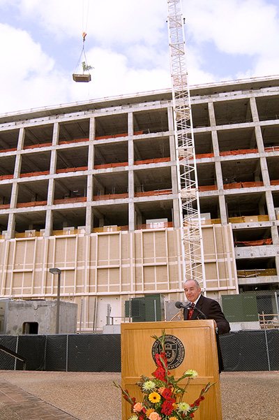 A speaker stands at a podium during construction of the Galveston National Laboratory at UTMB.