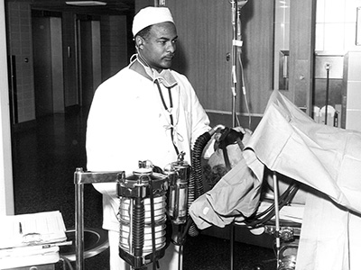Herman Barnett, the first African-American student to enroll at UTMB, provides care to a patient during his medical training.