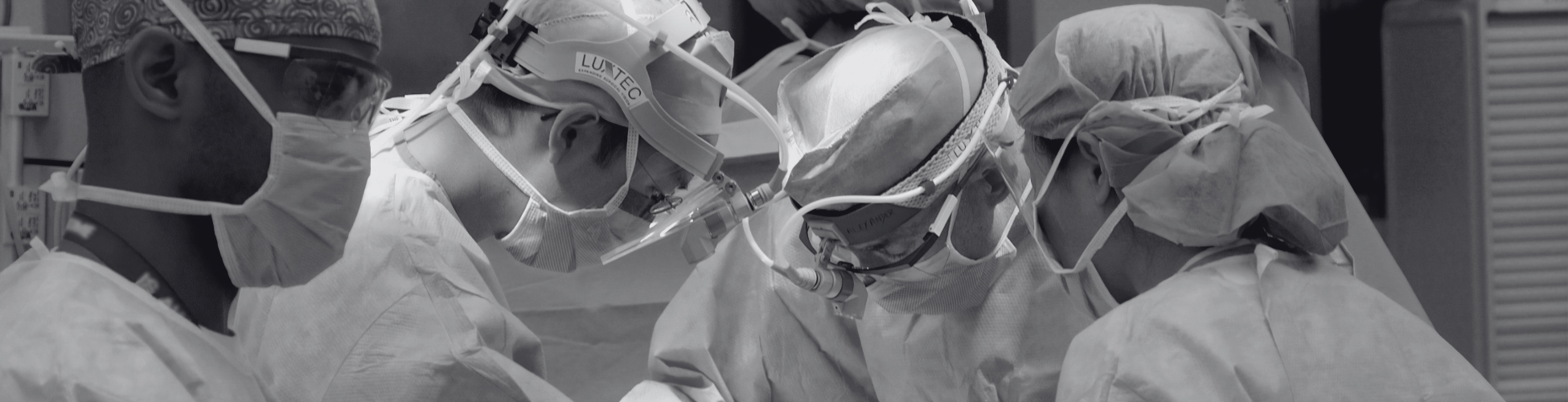 Surgical team wearing protective equipment performs a procedure in a hospital operating room.