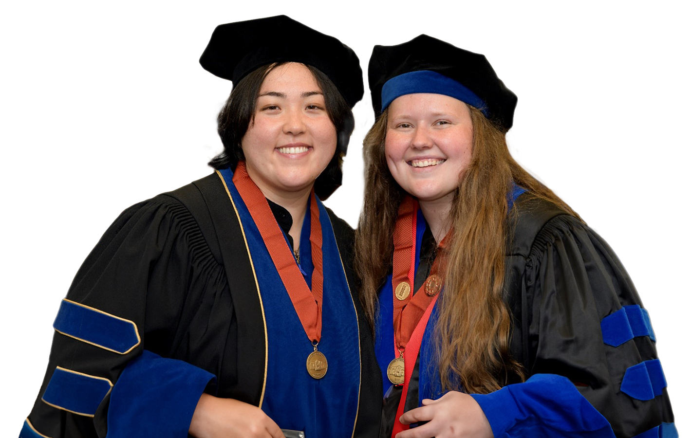 Two young women wearing graduation caps and smiling