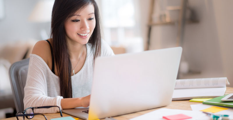 Student types on her laptop at a table.