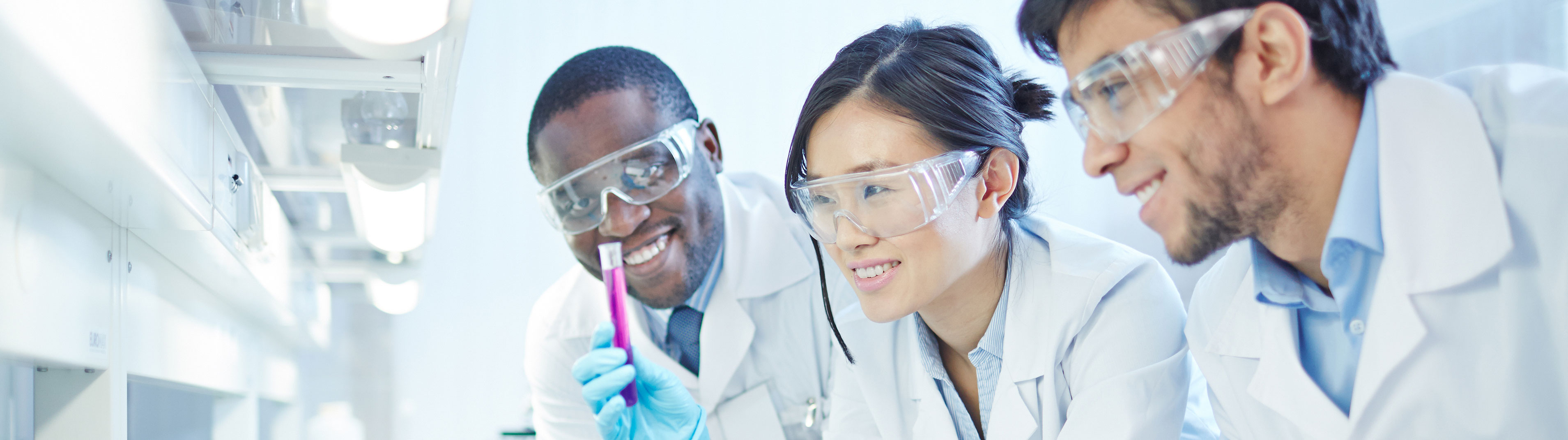 Three scientists are examining a test tube.