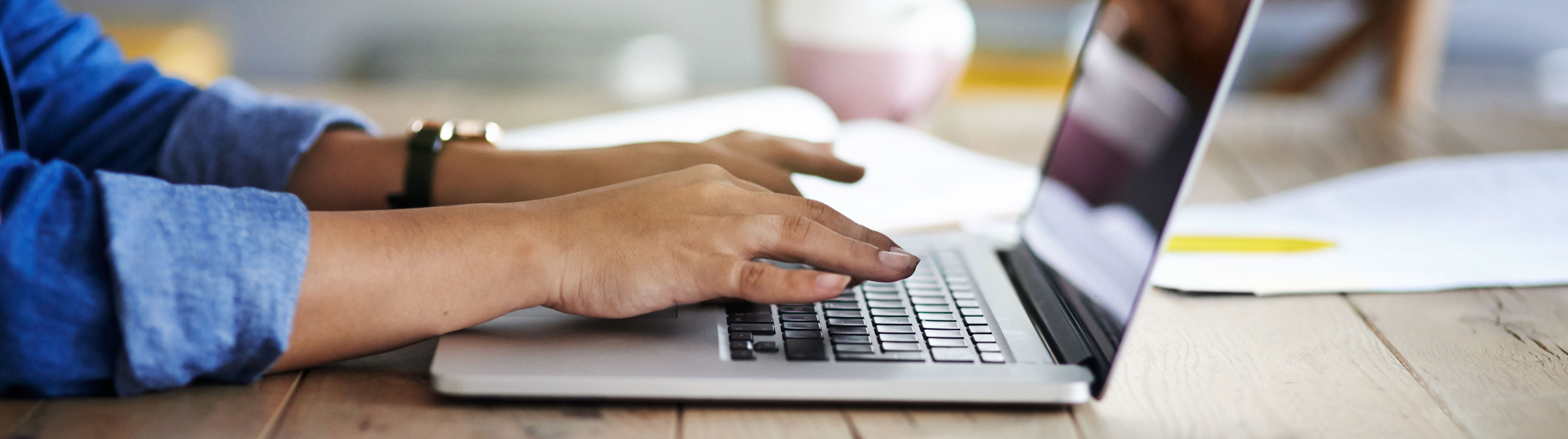 Close up of a person's hands typing on a laptop.