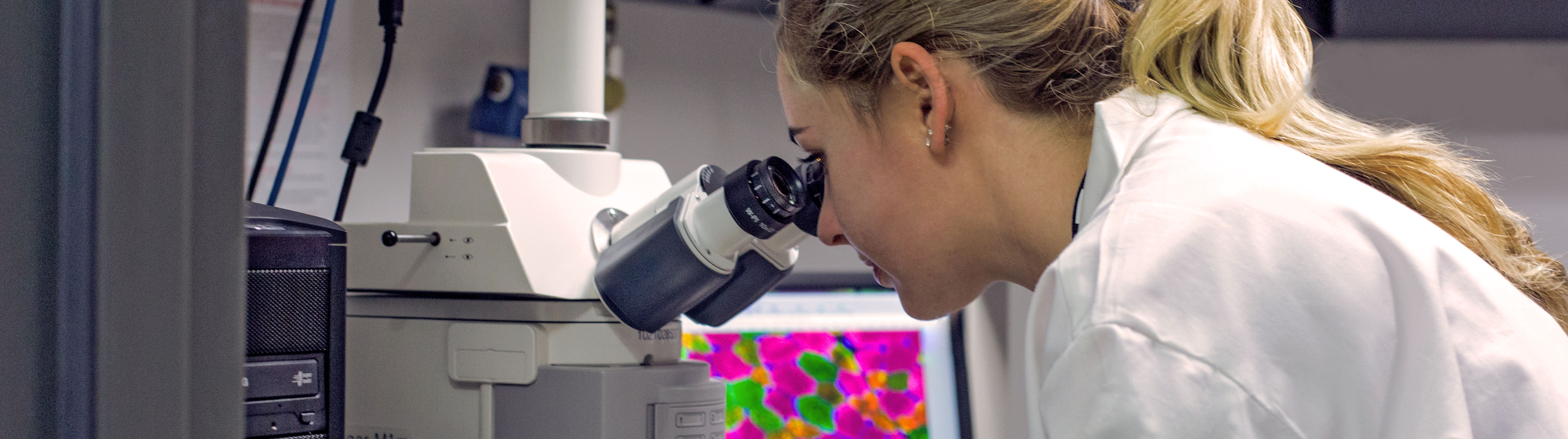 Student looks through telescope to look at colorful sample