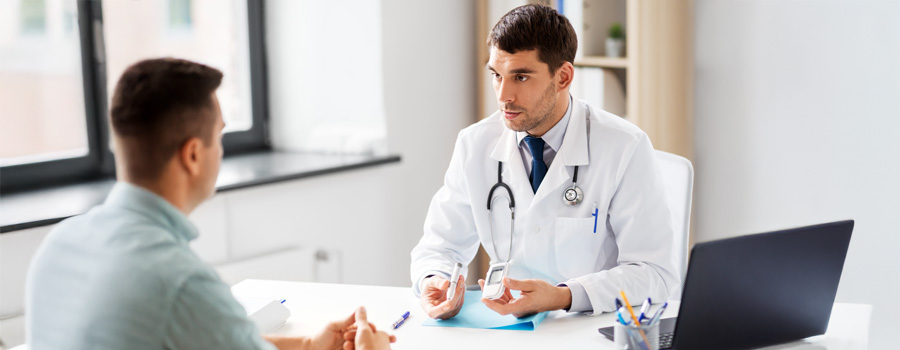 Male doctor showing male diabetic patient how to check his blood sugar