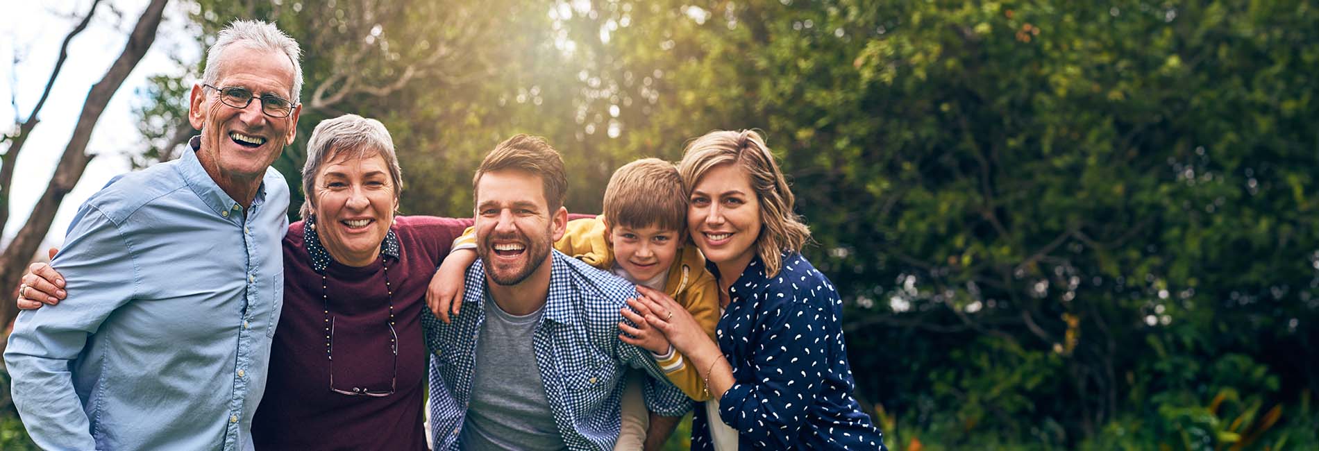A family grouped together and smiling outdoors