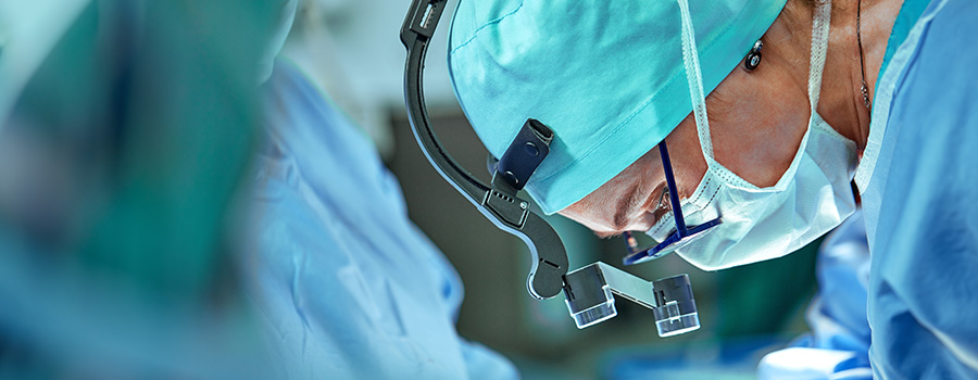 A UTMB cardiovascular surgeon wearing magnifying loupes performs a surgical procedure.