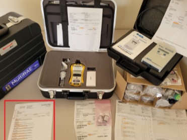 Open hard cases containing emergency tools, handheld device, paperwork, and organized supplies laid out on a table.